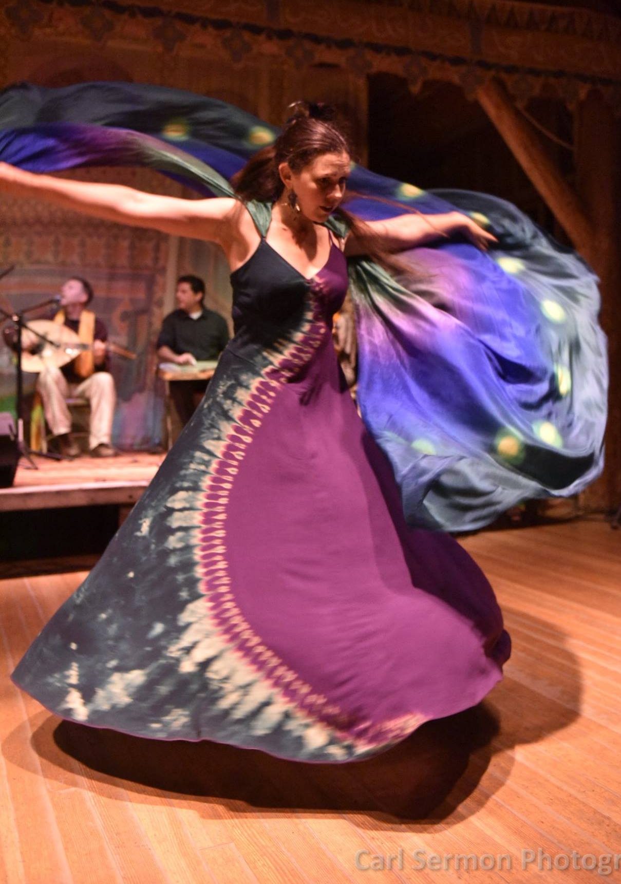 Dancer in purple and green dress turning holding large scarf